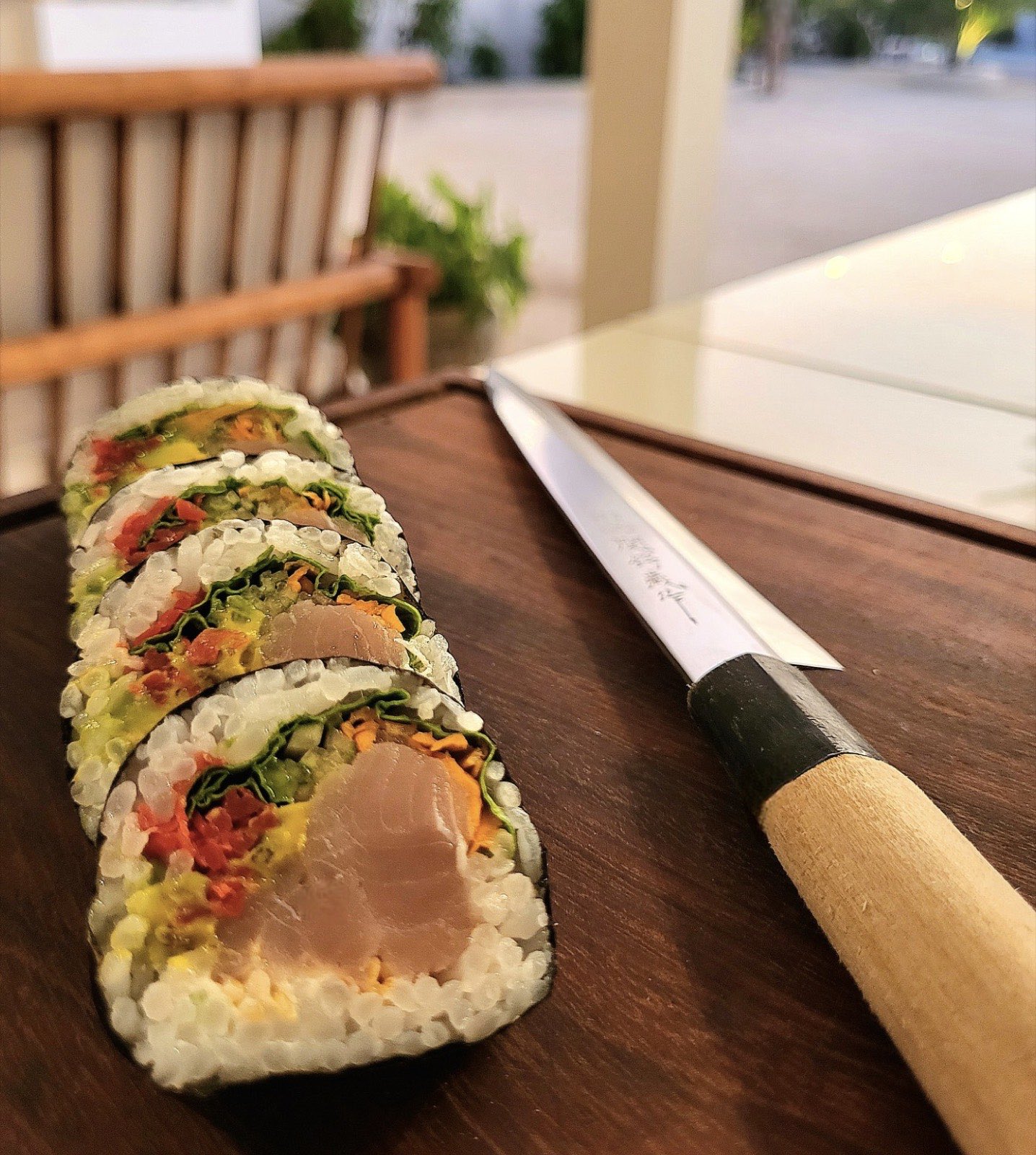 A sliced futomaki roll beside a traditional yanagiba sushi knife