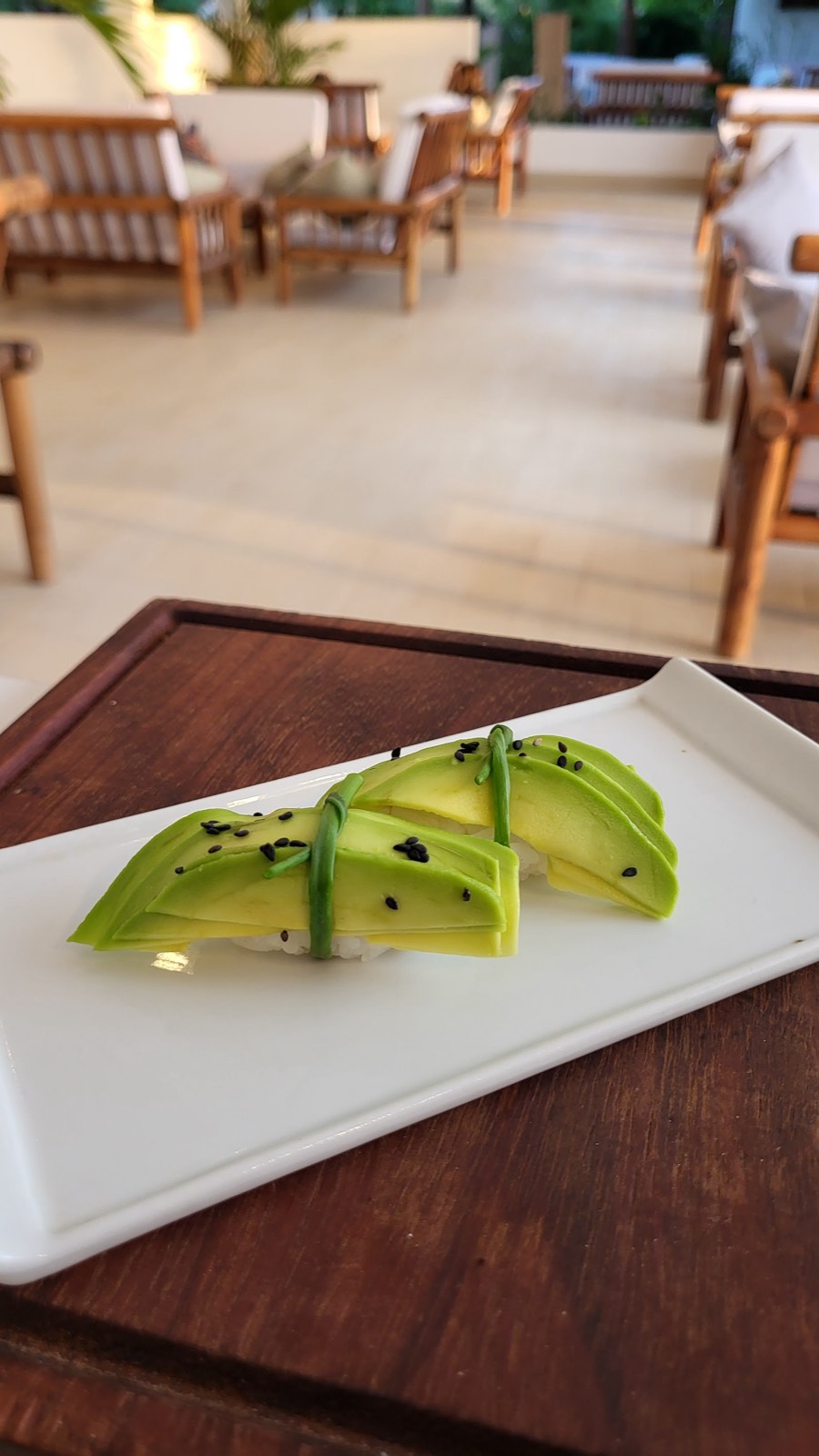 Elegant avocado nigiri topped with black sesame on a white plate